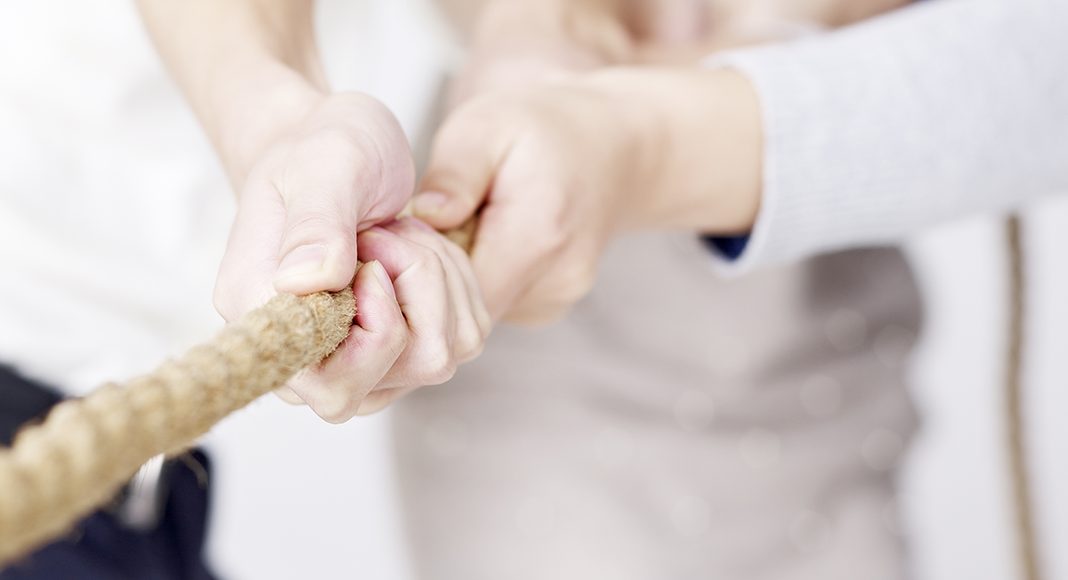 Zwei Personen ziehen gemeinsam an einem Seil.