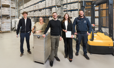 REISSWOLF B2B-Team mit Logistik-Experten und Sicherheitsbehälter im Archivlager für Datensicherheit und professionelle Aktenvernichtung.