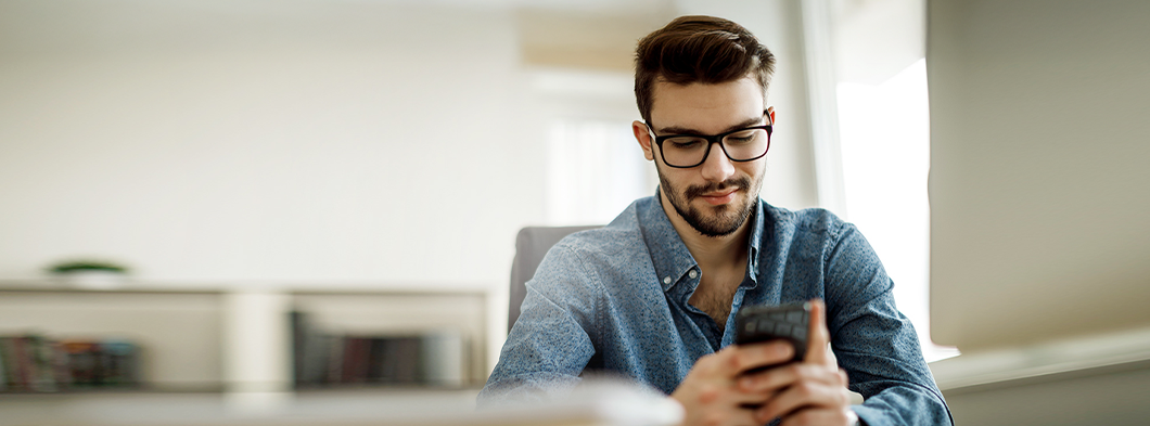 Mann im Büro überprüft seine Post digital auf seinem Smartphone.