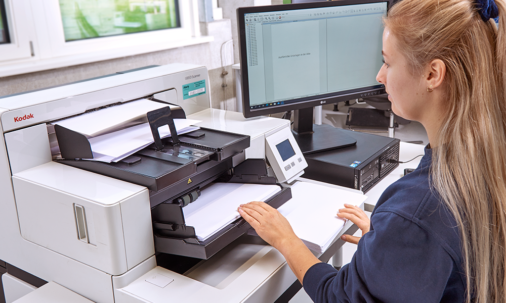 Mitarbeiterin scannt Papierdokumente mit professionellem Kodak-Dokumentenscanner