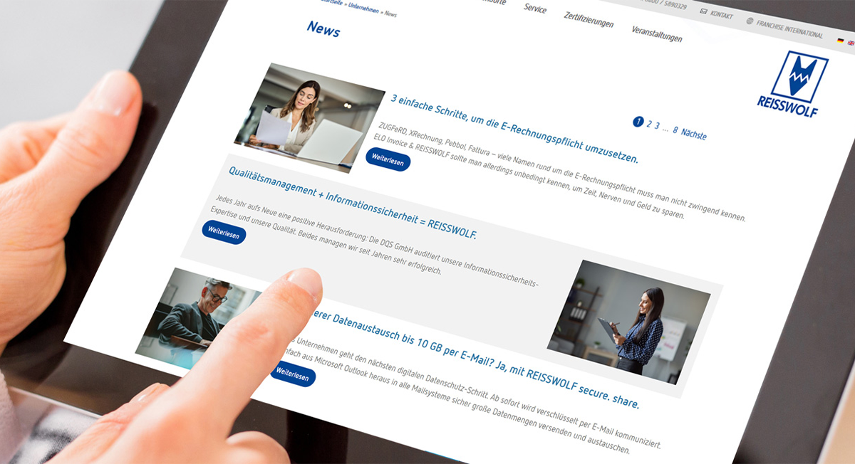 Hände halten ein Tablet, auf dem eine News-Webseite von REISSWOLF angezeigt wird.