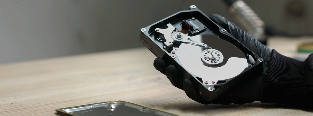 Hand eines Spezialisten hält eine Computerfestplatte zur sicheren Vernichtung.