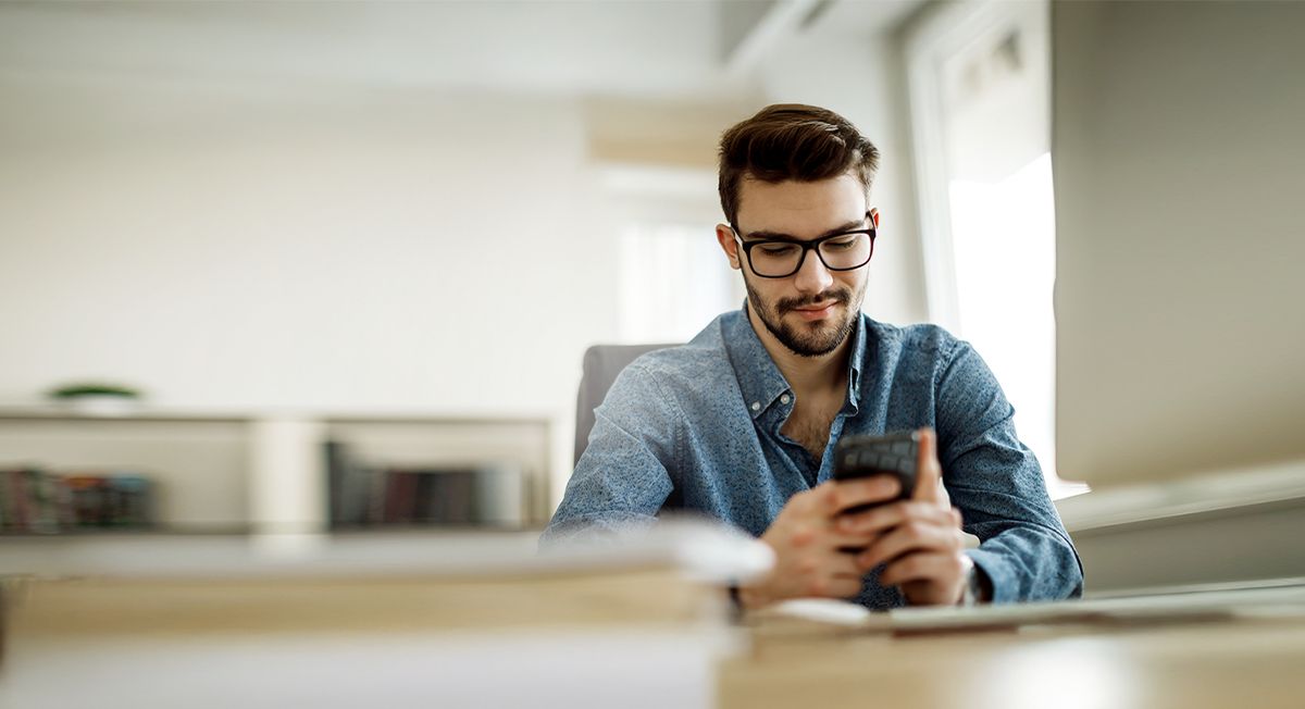 Mann im Büro überprüft seine Post digital auf seinem Smartphone.