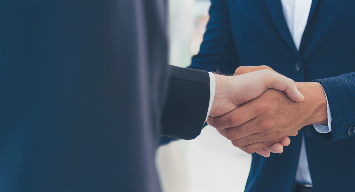 Two man in suits shake hands