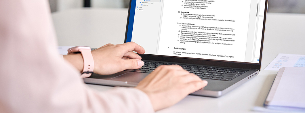 Hände bearbeiten Dokumente digital am Laptop in der REISSWOLF dok. suite.