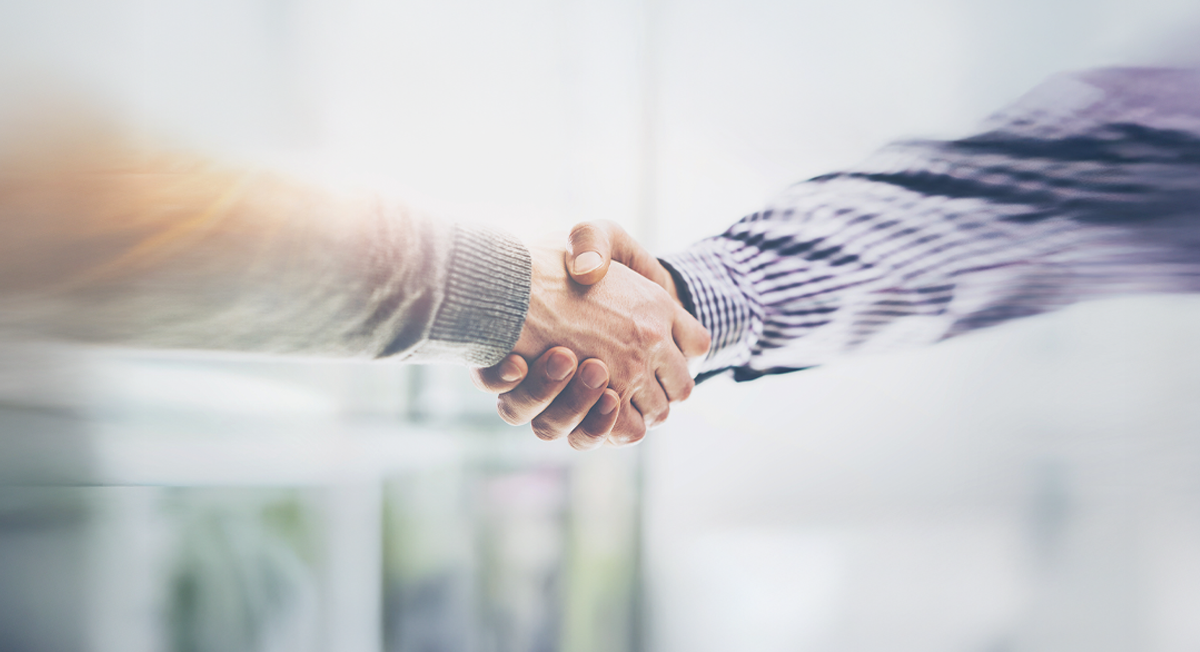 Händedruck zwischen zwei Geschäftspartnern über Dokumenten.