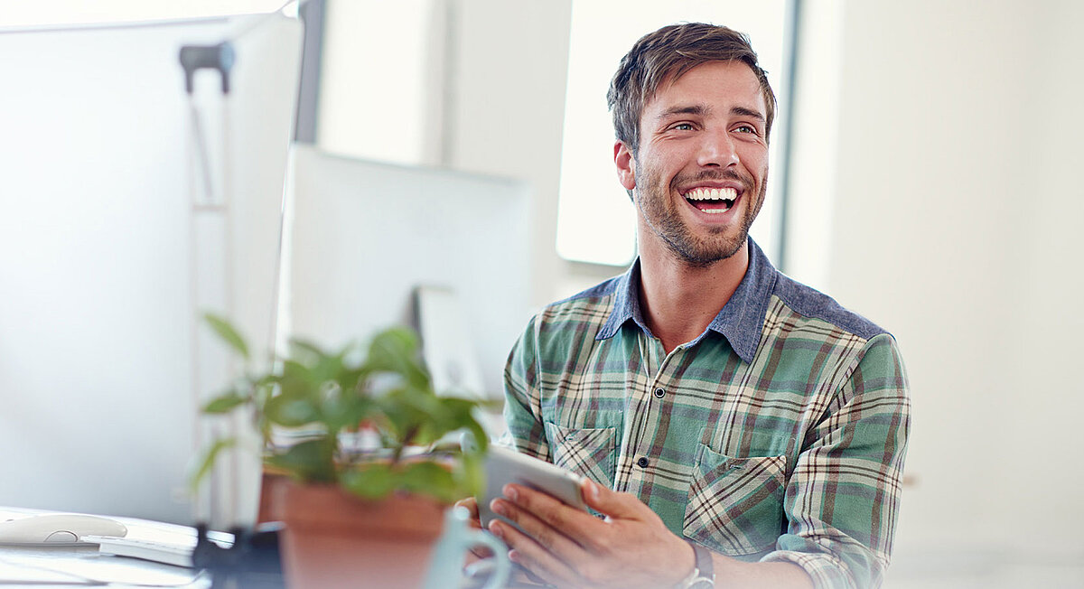 Ein Man am Schreibtisch mit einem Computer und einer Blume