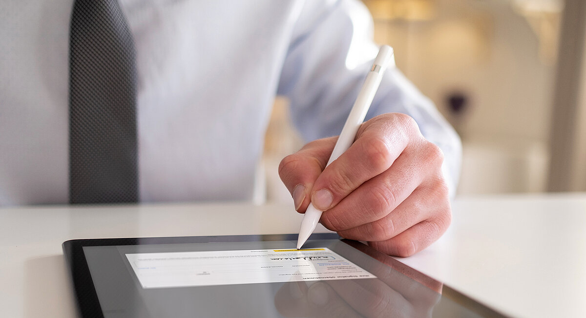 Ein Mann in einem Geschäftsanzug schreibt auf einem Tablet.