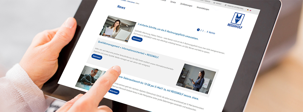 Hände halten ein Tablet, auf dem eine News-Webseite von REISSWOLF angezeigt wird.