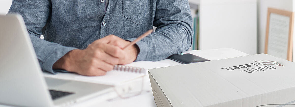 Nahaufnahme eines Schreibtisches im Home Office, mit Laptop, Schreibutensilien und der Dokumenten. Box. von REISSWOLF