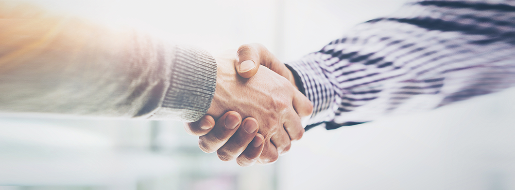 Händedruck zwischen zwei Geschäftspartnern über Dokumenten.